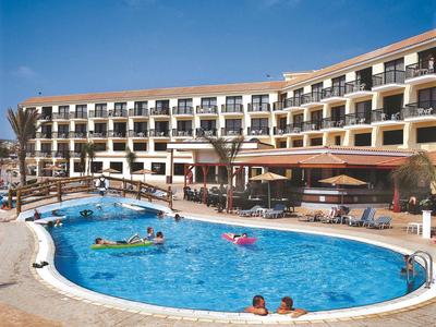 Hotel mit großem Außenpool, Liegestühlen und Gästen unter blauem Himmel