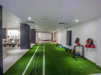 Área interior con césped artificial y equipo de fitness junto a zona de descanso en hotel moderno.