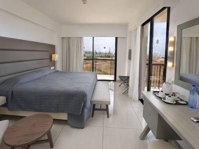 Modernes Hotelzimmer mit Doppelbett, Schreibtisch, großem Fenster und Balkon mit Blick ins Freie.