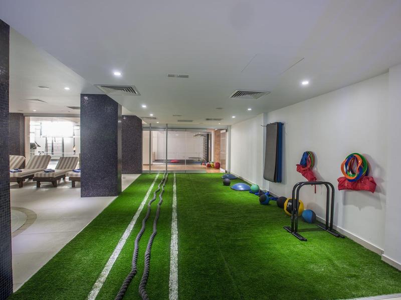 Innenbereich mit Kunstrasen und Fitnessgeräten in einem modernen Hotel.