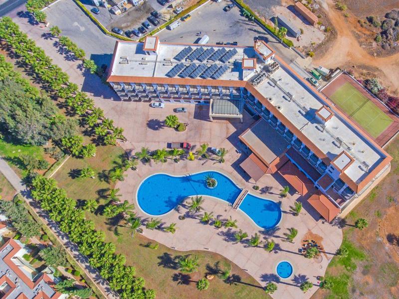 Luftaufnahme eines Hotels mit einem großen Pool und umliegenden Palmen