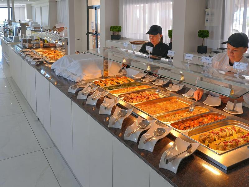 Buffet mit verschiedenen warmen Speisen in einem modernen Speisesaal.