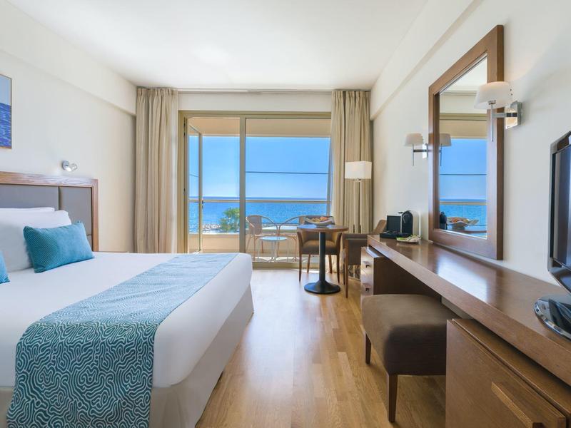 Modernes Hotelzimmer mit Doppelbett, Holzfußboden, großem Fenster und Meerblick.