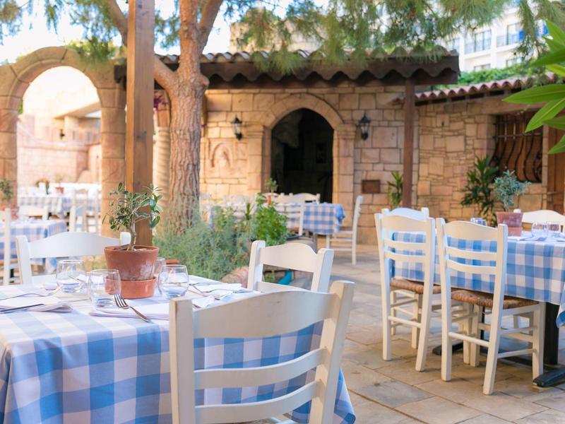 Gemütlicher Außenbereich eines Cafés mit blau-weiß karierten Tischtüchern und alten Backsteinwänden.