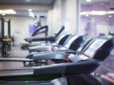 Varias cintas de correr en un gimnasio moderno y luminoso dentro de un hotel.
