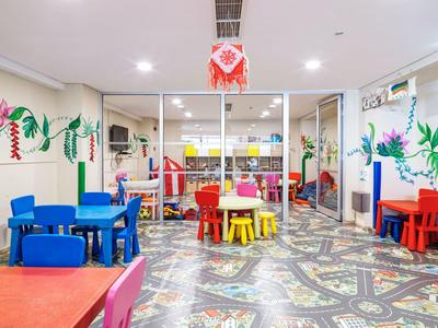 Brightly colored children's playroom with small tables, chairs, and wall decorations indoors.
