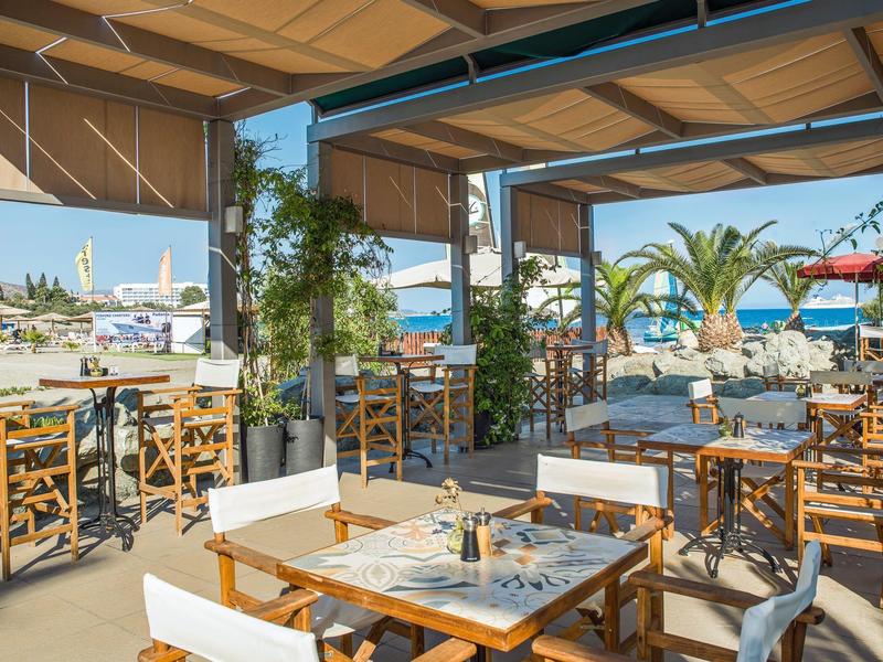 Open-air restaurant with wooden furniture and sea view at a sunny resort beach