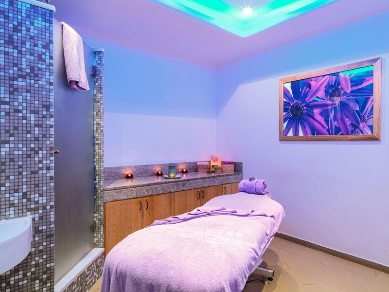 Cozy spa room with massage table, candles, and soft lighting for relaxation.