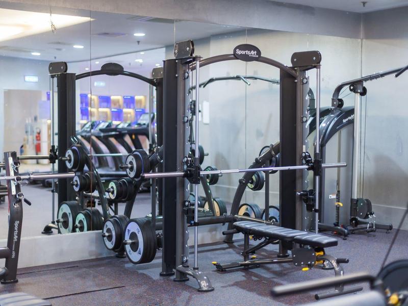 Modern gym with weightlifting and fitness equipment inside a hotel fitness room.