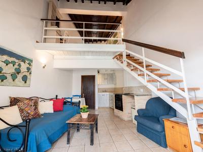 Heller Wohnbereich mit Treppe, blauen Sofas und modernem Dekor in einer Ferienwohnung.