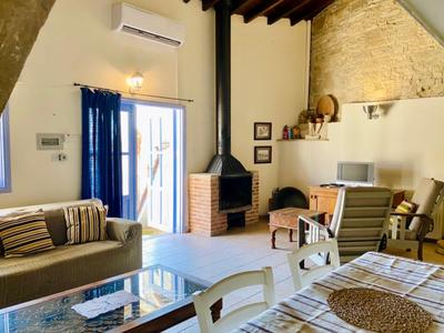 Hell eingerichtetes Wohnzimmer mit Kamin, Sofa, Sesseln und großem Glas-Couchtisch.