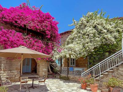 Innenhof mit blühenden pinken und weißen Blumen an Steinmauern unter blauem Himmel