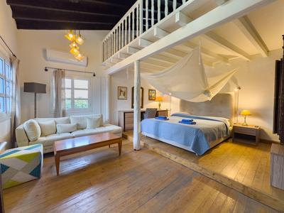 Gemütliches Hotelzimmer mit Doppelbett, Sitzecke und Holzboden unter einer Galerie.