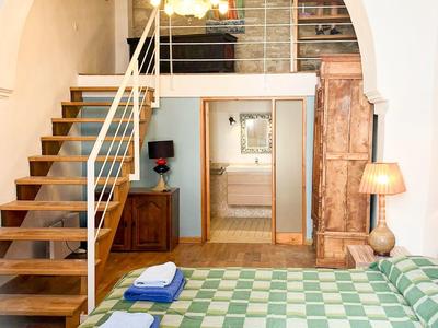 Helles Schlafzimmer mit Holztreppe und grün kariertem Bett, Handtücher versteckt.