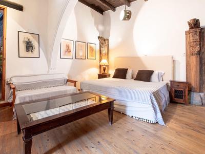 Gemütliches Hotelzimmer mit Doppelbett, Holzboden und geschwungenen Deckenbalken.