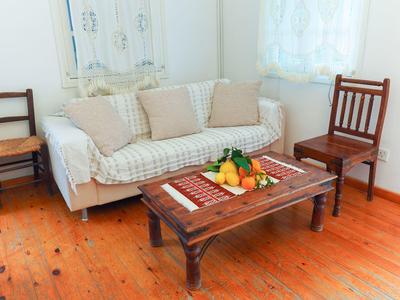 Gemütliches Wohnzimmer mit Couch, zwei Holzstühlen und einem Holztisch mit Obstplatte.