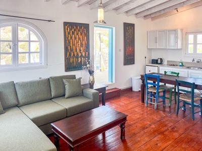 Helles Wohnzimmer mit grauem Sofa, Holztisch und angrenzender Küche mit blauem Essbereich.