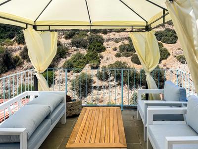 Gemütliche Sitzecke mit Sofas und Sesseln unter einem Pavillon mit Blick auf felsige Hügel.