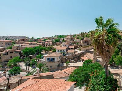 Blick auf ein Dorf mit roten Ziegeldächern und Palmen unter klarem Himmel