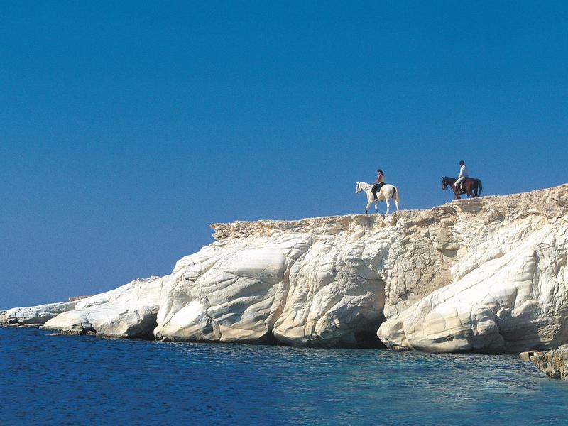 Haus mit terrakottafarbenen Dächern, blau gefliestem Pool und sonnigem, bewölktem Himmel.