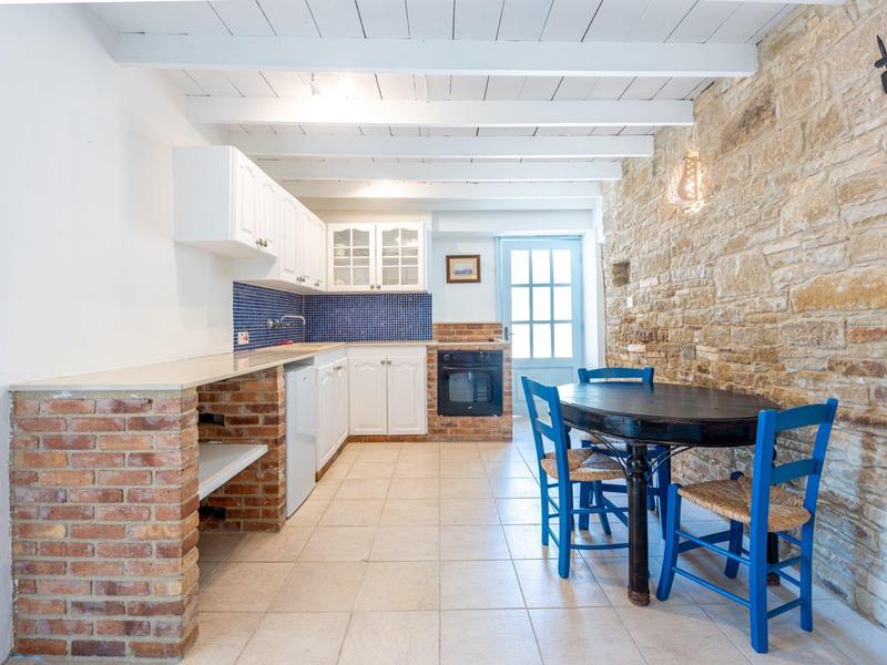 Helle Küche mit weißem Holzdecke, Steinwand und blauem Essbereich mit vier Stühlen.