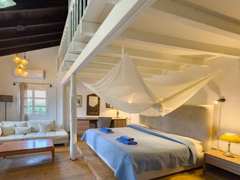 Hell eingerichtetes Schlafzimmer mit Himmelbett und Sitzbereich unter Galerie