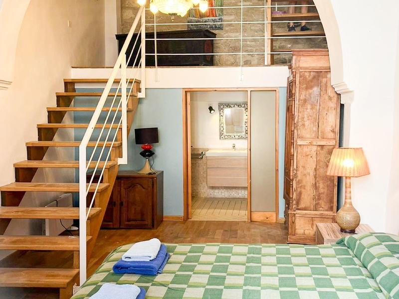 Helles Schlafzimmer mit Holztreppe und grün kariertem Bett, Handtücher versteckt.