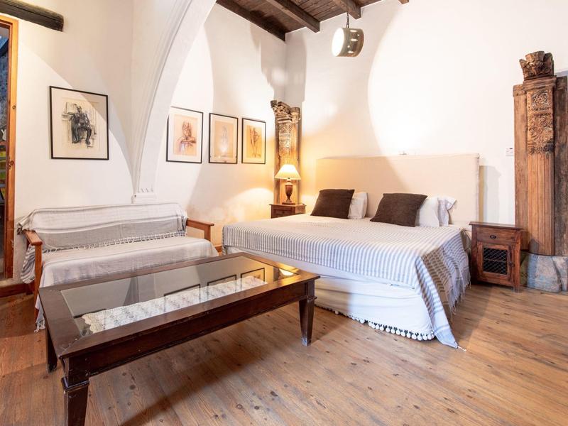 Gemütliches Hotelzimmer mit Doppelbett, Holzboden und geschwungenen Deckenbalken.