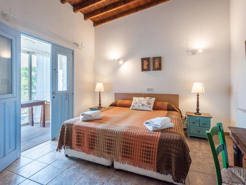 Helles Schlafzimmer mit rustikaler Decke, großem Bett und zwei Nachttischen in einem Hotelzimmer.