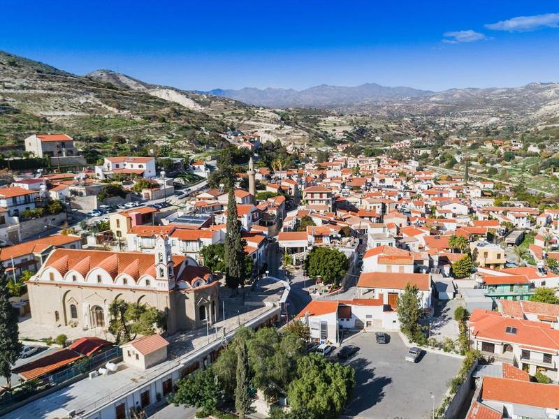 Luftaufnahme einer malerischen Stadt mit roten Dächern und Bergen im Hintergrund