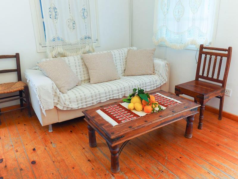 Gemütliches Wohnzimmer mit Couch, zwei Holzstühlen und einem Holztisch mit Obstplatte.