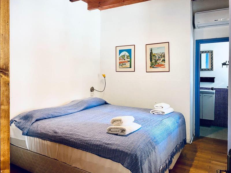 Gemütliches Doppelbett mit blauer Bettdecke und Handtüchern in einem hellen Hotelzimmer.