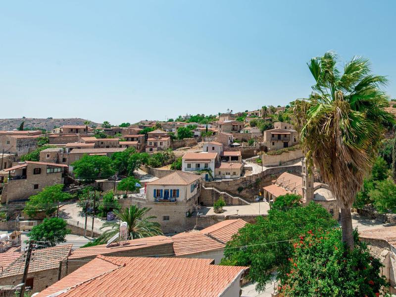 Blick auf ein Dorf mit roten Ziegeldächern und Palmen unter klarem Himmel