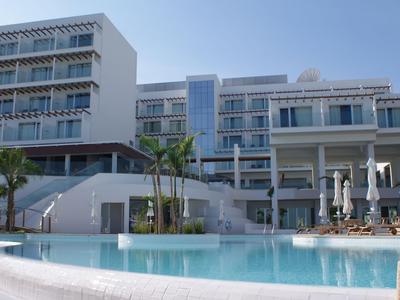 Hotel moderno de varios pisos con una gran piscina en primer plano.