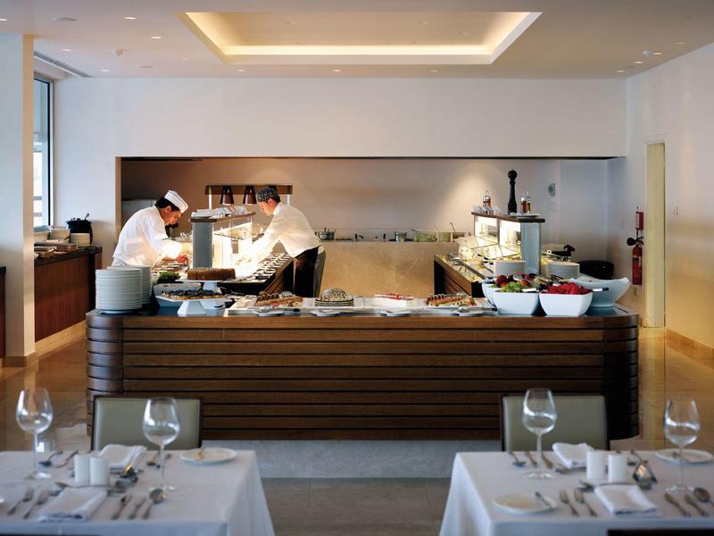 Deux chefs préparent des plats au buffet dans un restaurant moderne.