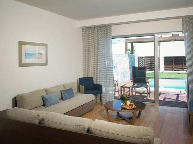 Coin salon d'hôtel confortable avec canapés, fauteuils et vue sur terrasse avec piscine.