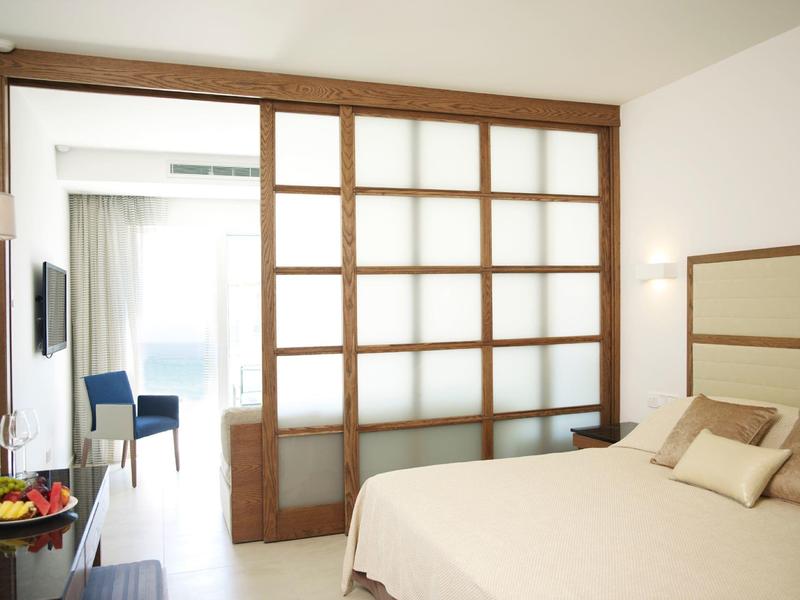 Chambre d'hôtel moderne avec lit double et porte coulissante vers un espace lumineux