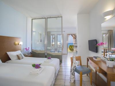 Nowoczesny pokój hotelowy z dwoma pojedynczymi łóżkami, biurkiem i szklaną ścianą do łazienki.