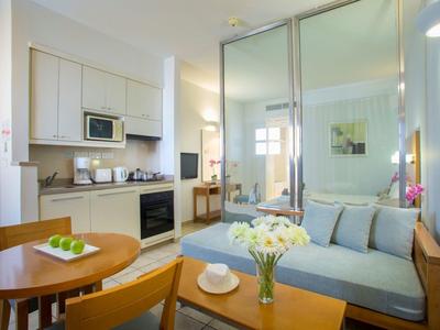 Kleine, moderne Küchen-Wohnzimmer-Kombination mit Holzmöbeln, Sofa, Tisch und weißen Wänden.