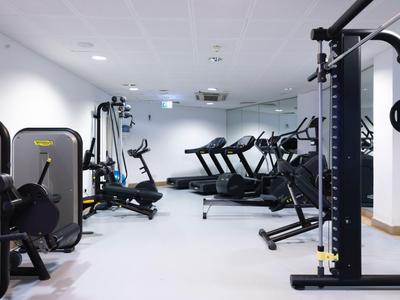 Nowoczesna siłownia z maszynami treningowymi i bieżniami w jasnym pomieszczeniu.