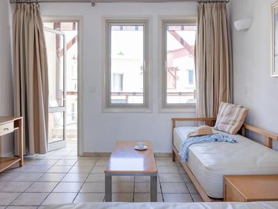 Habitación de hotel luminosa con puertas al patio, cortinas y zona de estar acogedora con sofá y mesa.