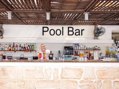 Vista interior de un bar de piscina elegante con revestimiento de piedra y techo de madera.