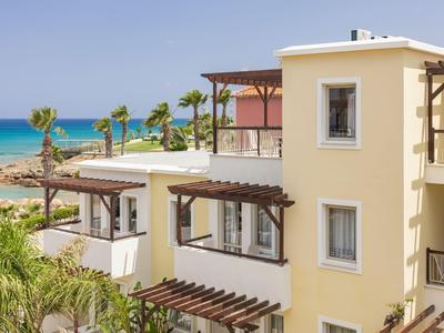Edificio de hotel amarillo con balcones cerca de la playa y vista al mar azul bajo un cielo despejado.