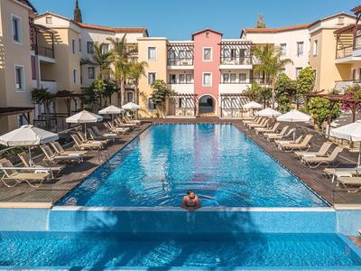 Dziedziniec z prostokątnym basenem i leżakami w hotelu śródziemnomorskim.