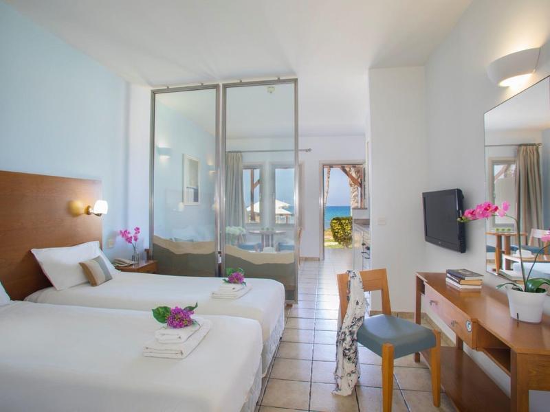 Modernes Hotelzimmer mit zwei Einzelbetten, hellen Wänden, Fliesenboden und großzügigem Bad.