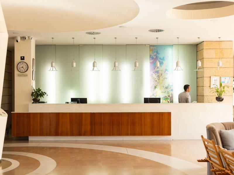 Moderne Hotellobby mit hellem Empfangstresen, Pflanzen und bequemen Sitzmöbeln.