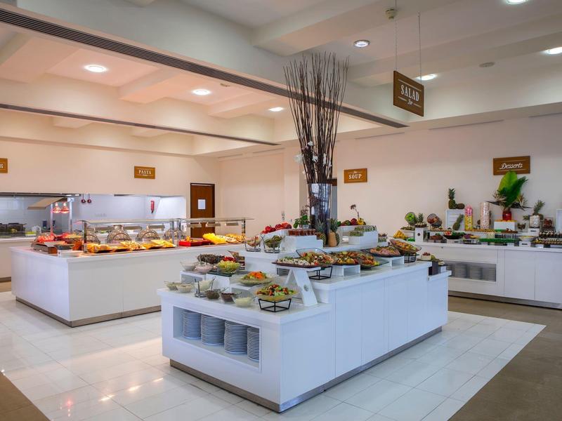 Großer Buffetbereich mit verschiedenen Speisen auf weißen Buffettischen in hellem Raum