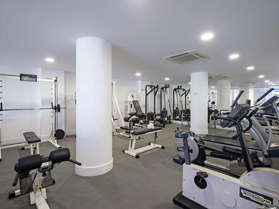 Moderner Fitnessraum mit Trainingsgeräten und gut beleuchtetem Innenraum.