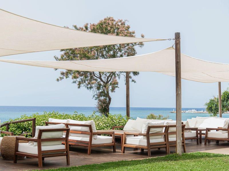 Outdoor-Lounge mit Holzmöbeln und Segeltuchüberdachung mit Meerblick