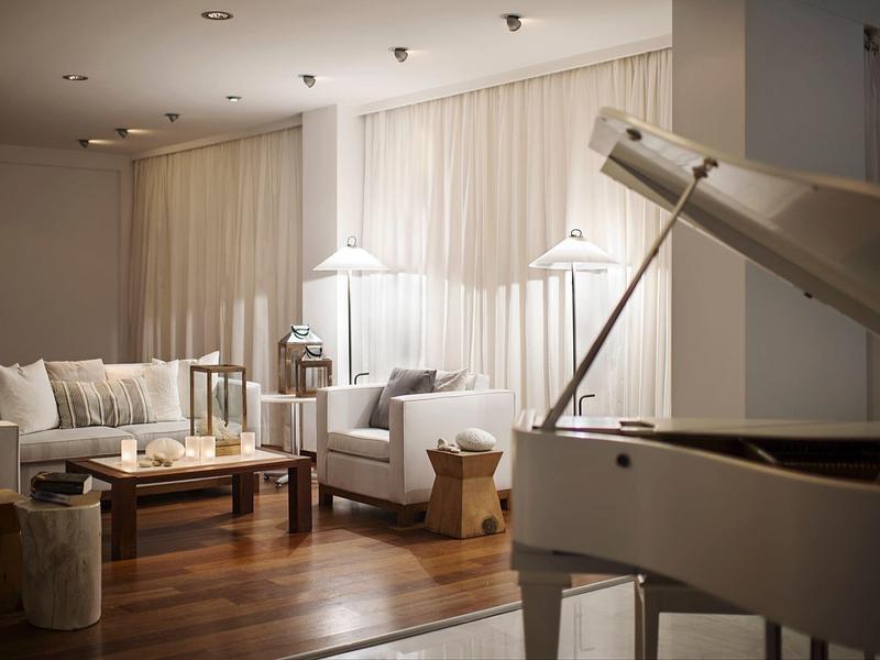 Elegantes Wohnzimmer mit weißem Flügelklavier, bequemen Sofas und Holzboden.